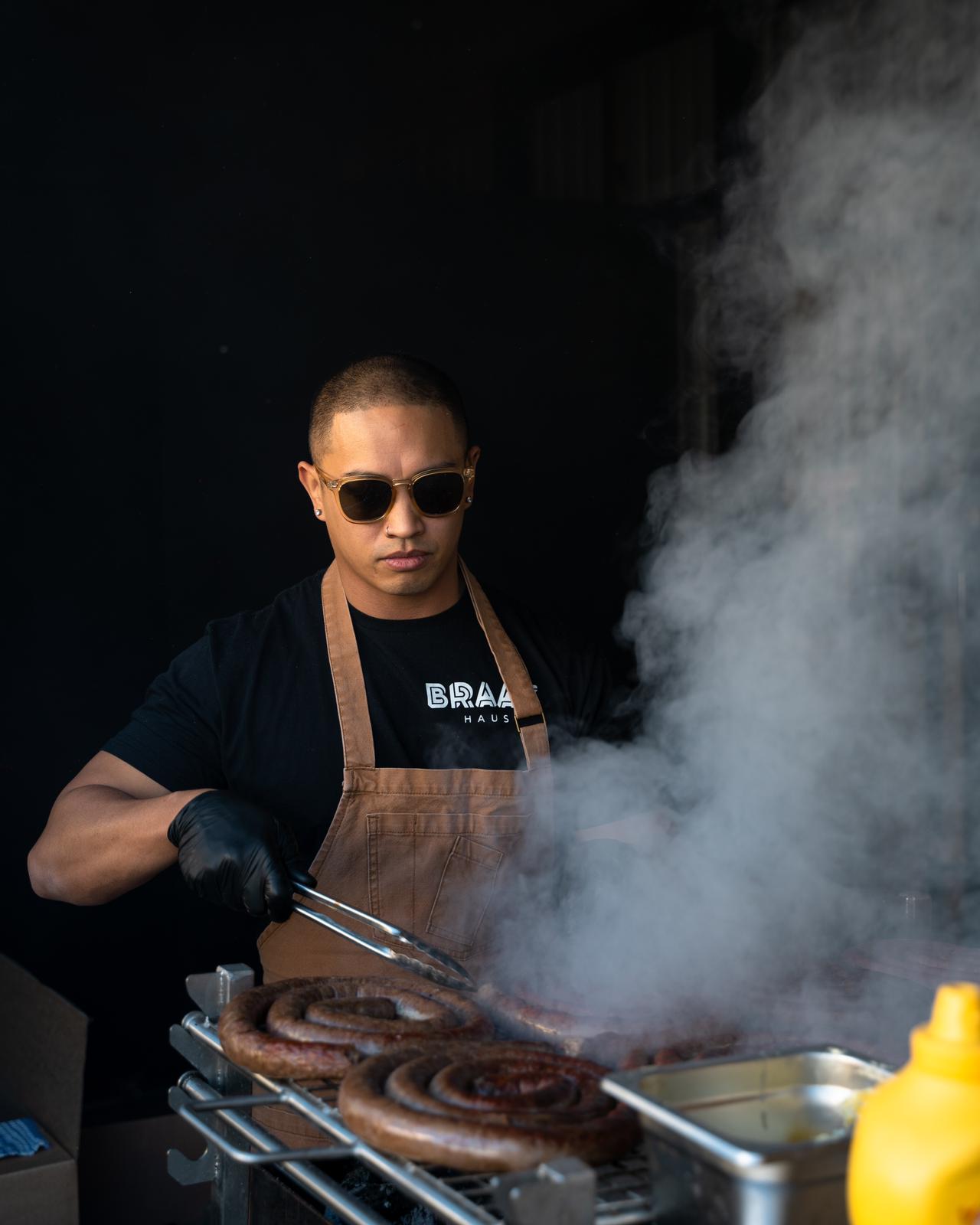 Chef wearing sunglasses cooking sausages on a barbeque