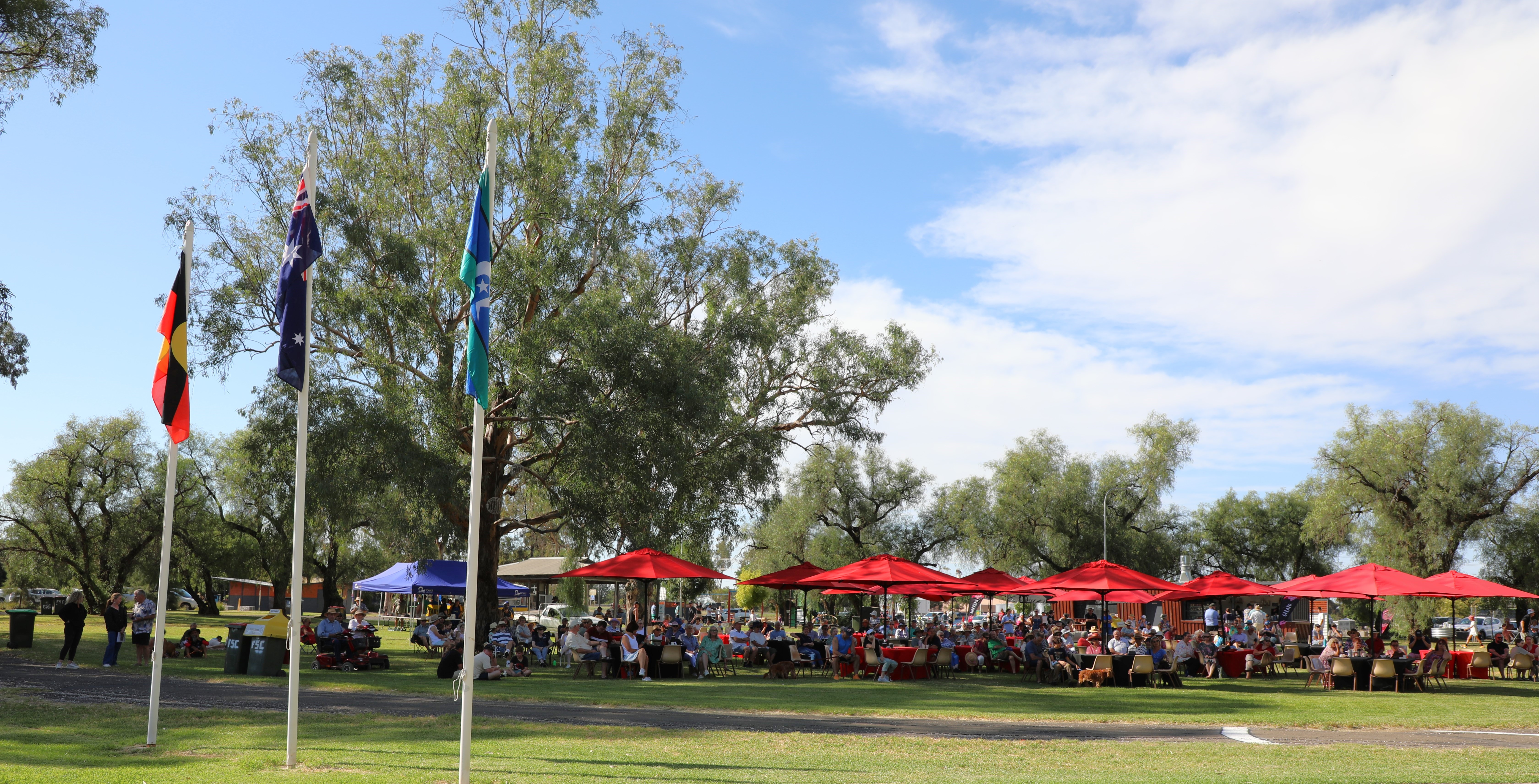 Crowd of people sitting under red umbrellas 